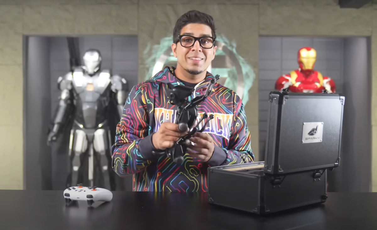Load video: A presenter holding a Sirius robot dog behind a table with a gamepad and carrying case.
